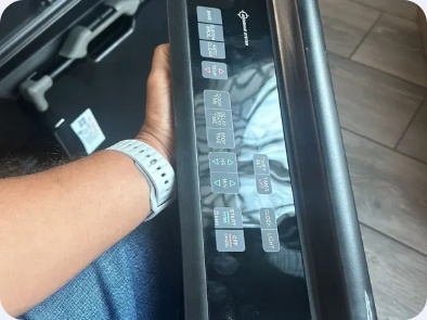 Black oven and range control panel held beside an open appliance cabinet.