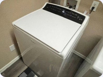 White GE top-load washing machine in a residential laundry space.