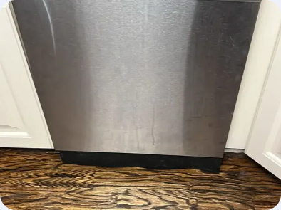 Lower stainless steel dishwasher door and black toe-kick between kitchen cabinets.