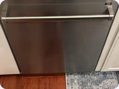 Stainless steel built-in dishwasher with a horizontal bar handle beside kitchen cabinetry.