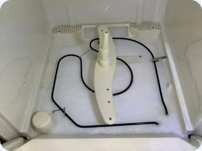 White dishwasher tub with the lower rack removed, showing the spray arm and heating element.