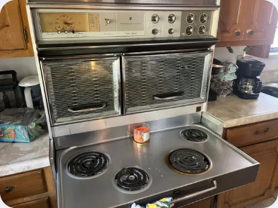 Vintage electric cooking appliance with exposed coil burners and upper oven doors.
