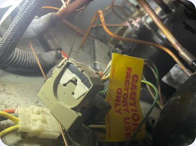 Close view of electrical components and wiring beside refrigerator compressor tubing.