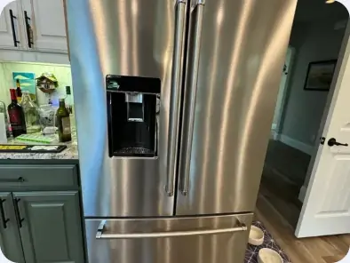Stainless steel French-door refrigerator with a through-door dispenser and lower freezer drawers.