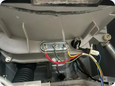 Close view of a washer tub's heating-element mounting plate, electrical terminals and wiring.