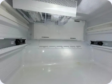 Empty refrigerator interior with the upper ice-making assembly and shelf supports visible.