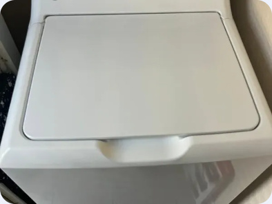Angled view of a white top-load washer with its lid closed.