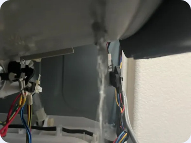 Open washer service area showing tub-side wiring and electrical connectors.