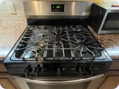 Stainless and black freestanding gas range with cast burner grates and front-mounted knobs.