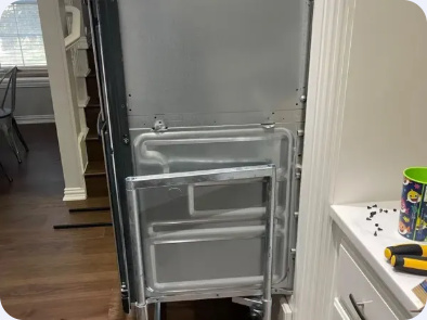 Built-in oven pulled forward from its cabinet, exposing the metal side panel.