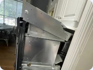 Angled view of an oven chassis pulled out of kitchen cabinetry for access.