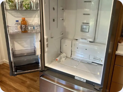 Open French-door refrigerator with shelves removed and its interior service area visible.