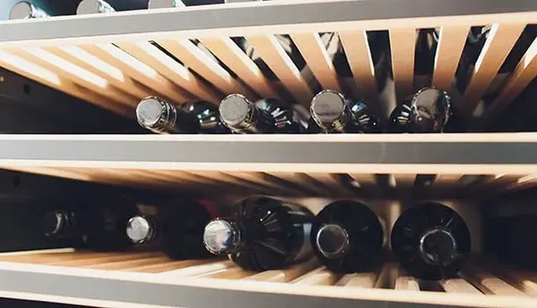 Wine Cooler Repair in Springfield MO | Service Brothers Wine bottles stored on wooden shelves inside a wine cooler