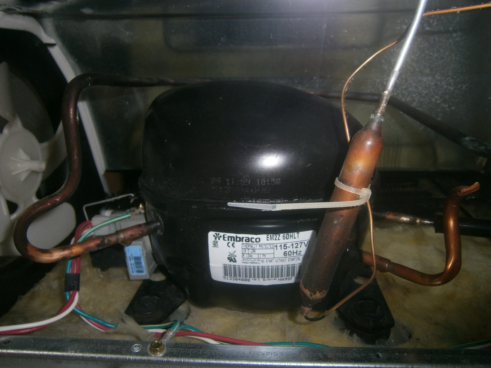 Refrigerator compressor and fan | Service Brothers Our Work Refrigerator compressor, copper tubing and condenser fan with the access panel removed