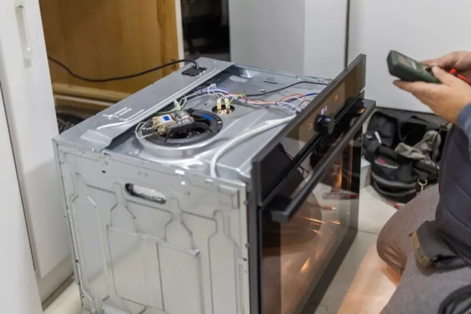Technician checking an oven with its outer panel removed